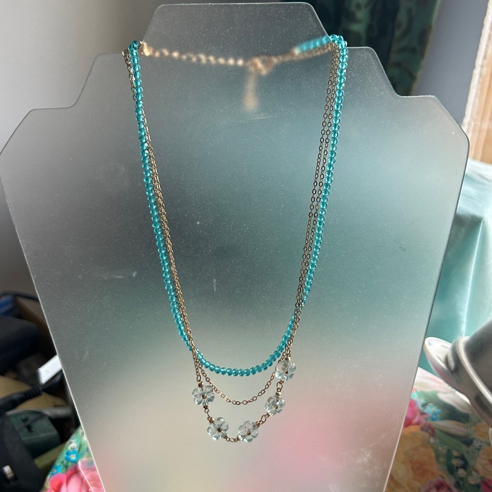 Triple strand necklace With gold tongue, chain and glass flowers, and beads